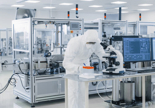 Shot of Sterile Pharmaceutical Manufacturing Laboratory where Scientists in Protective Coverall's Do Research, Quality Control and Work on the Discovery of new Medicine.